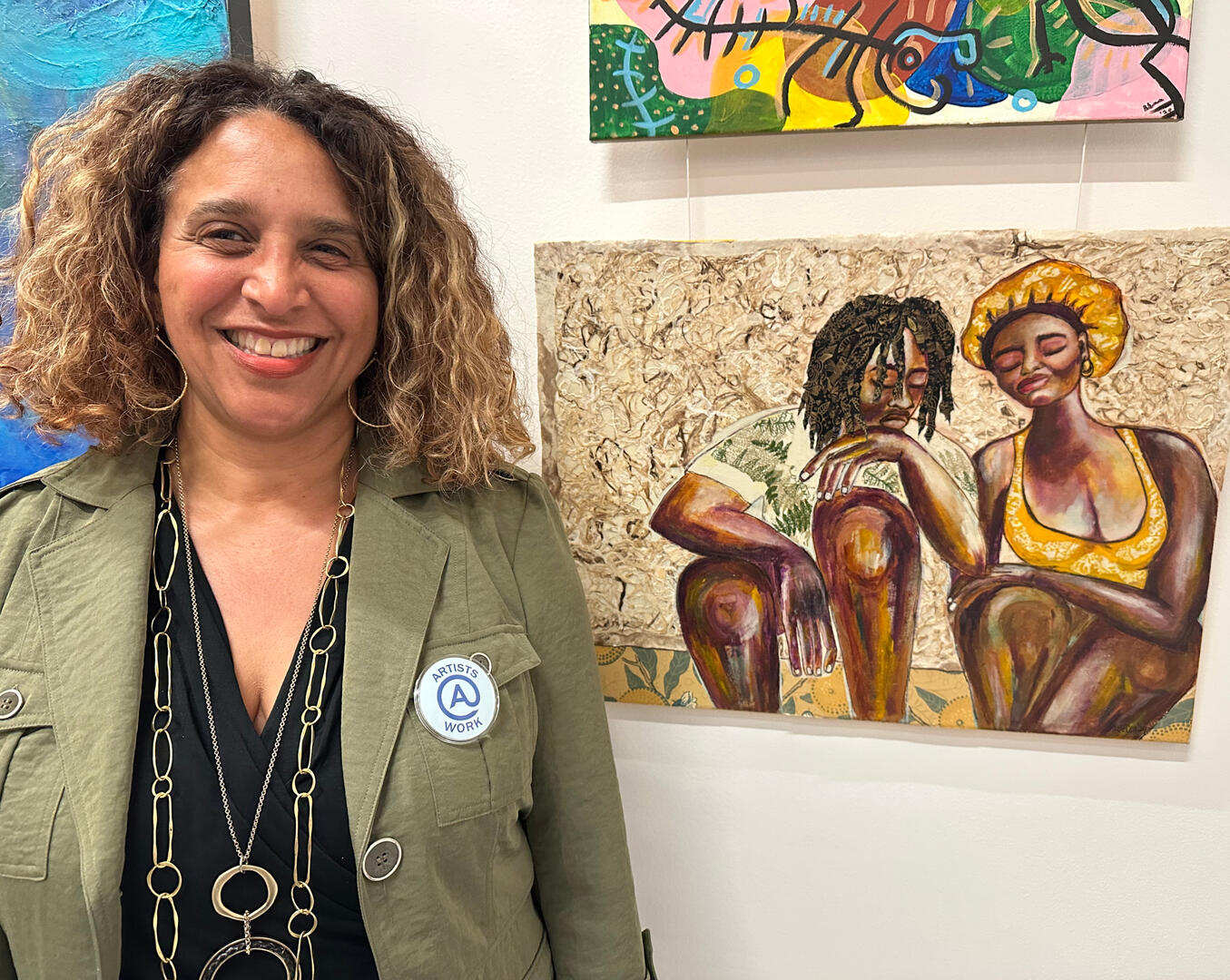 artist wearing "artists at work" badge next to their artwork