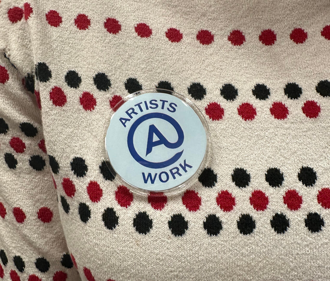 close up of "Artists at Work" badge worn